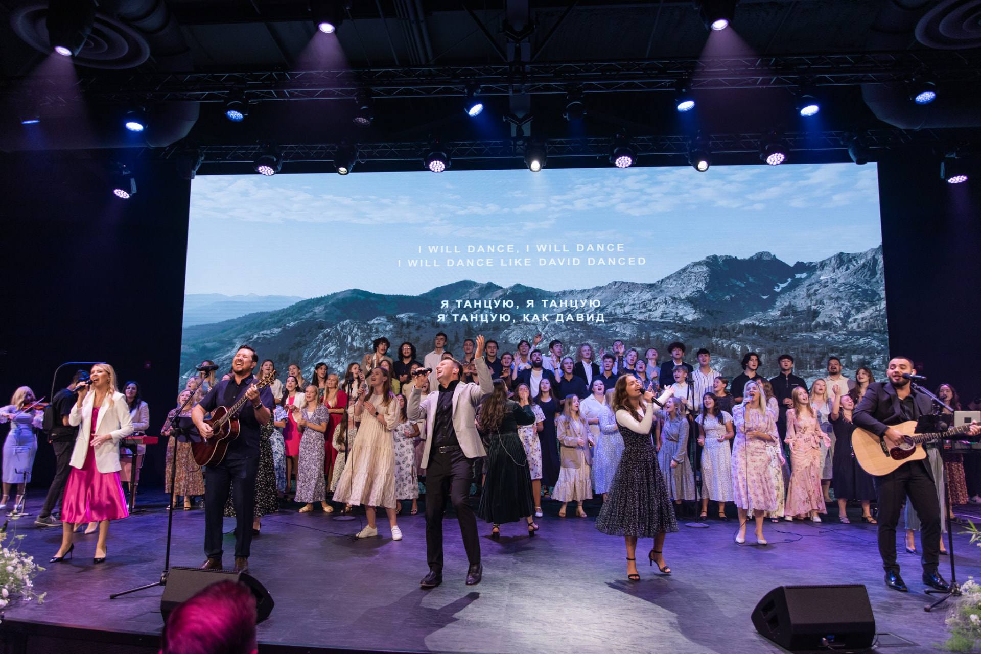 Worship team and choir on stage during a Church of Truth service, with a mountain scene on the screen behind them